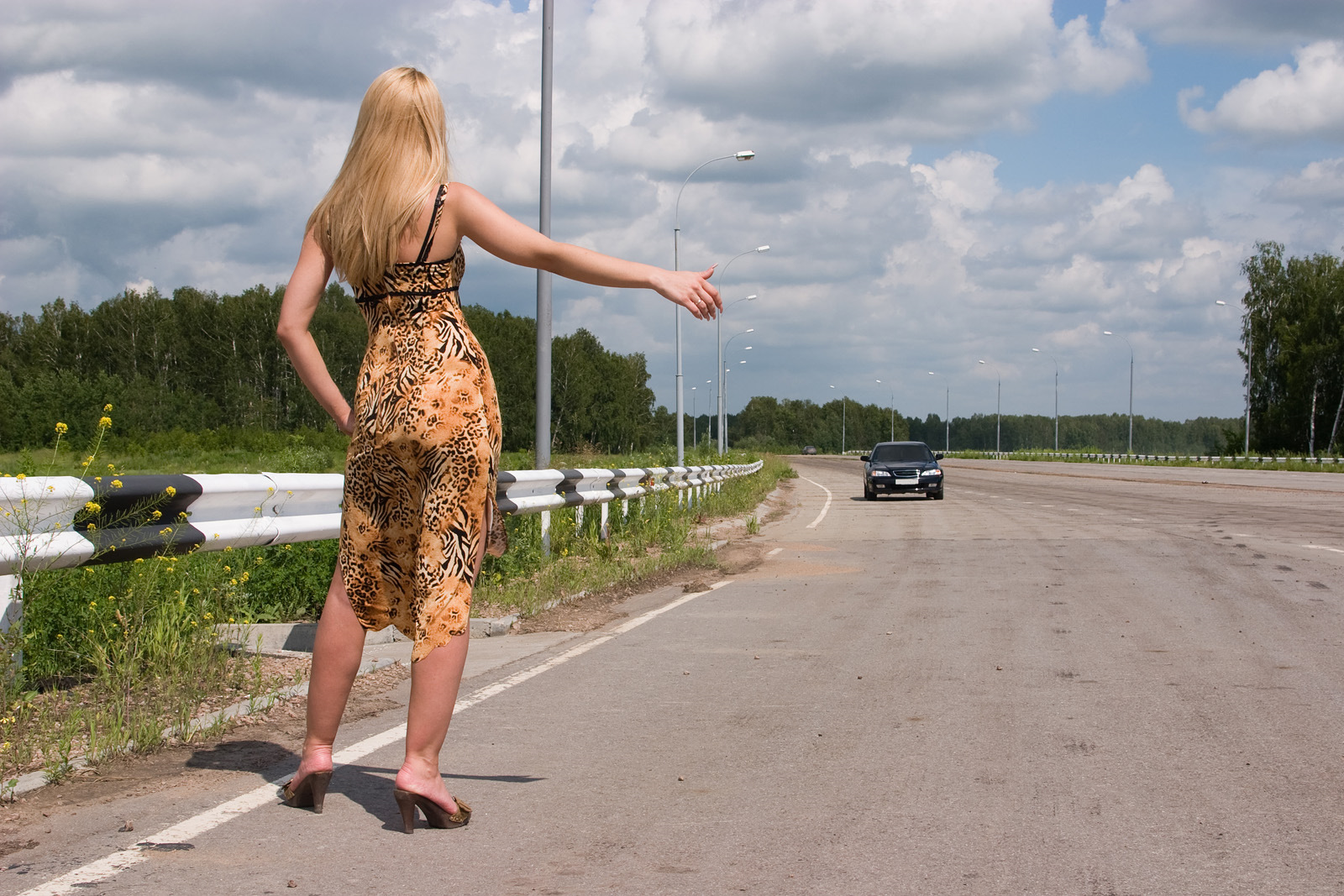Молодая блондинка в короткой юбке прогуливается на парковке для дальнобойщиков