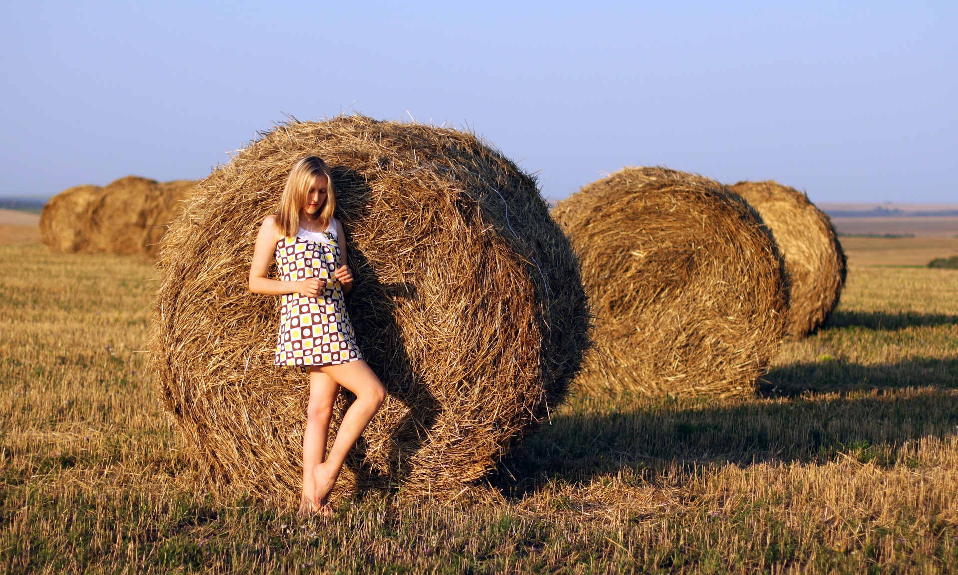 Женщина за 40 позирует в поле на сеновале из тюков