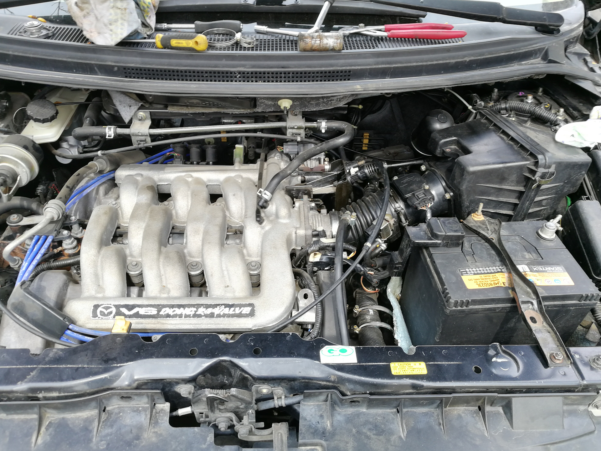 Двигатель мазда мпв 2.5. Mazda MPV 3.0 под капотом. Мазда МПВ 2.5 бензин. АКБ Мазда МПВ 2.5. Mazda MPV под капотом.
