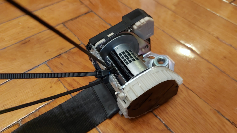 Разматываем ремень и фиксируем катушку. Мы, в этот раз, использовали металлическую вязальную спицу. Вставили её в технологическое отверстие враспор и зафиксировали стяжками. Получилось весьма надёжно. — Ford Focus Hatchback II