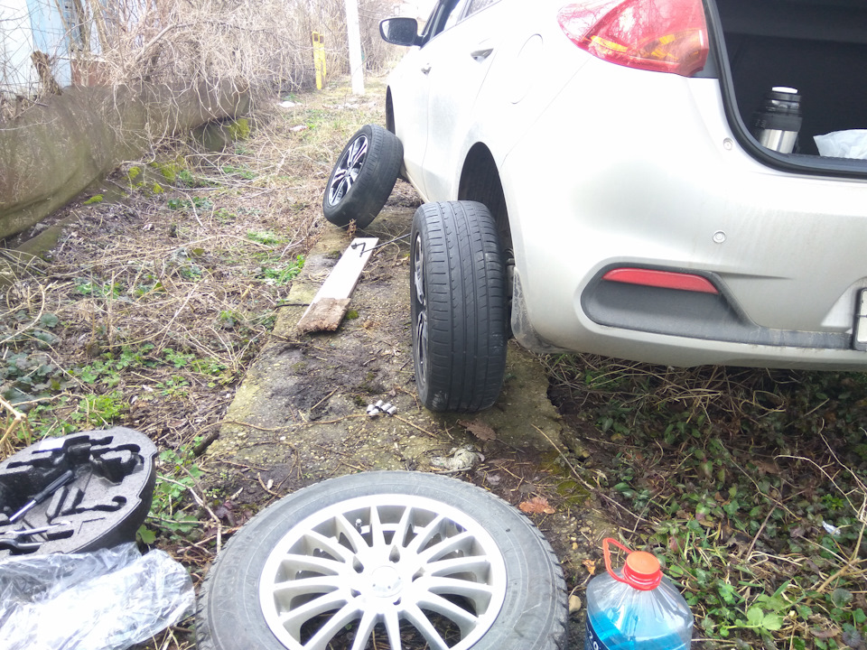 скинули шину. перекинуть колеса местами. перекинуть колеса. замена колеса на автомобиле. скинули шину.