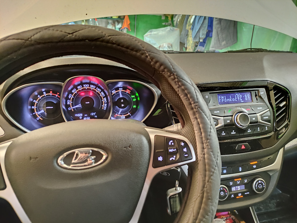 13,4 В по приборке. Включен ближний, туманки, обогрев лобового, обогрев заднего/зеркал, печка на 2 деления, магнитола — Lada Vesta SW Cross (1G). Запчасти на фото: 1091040