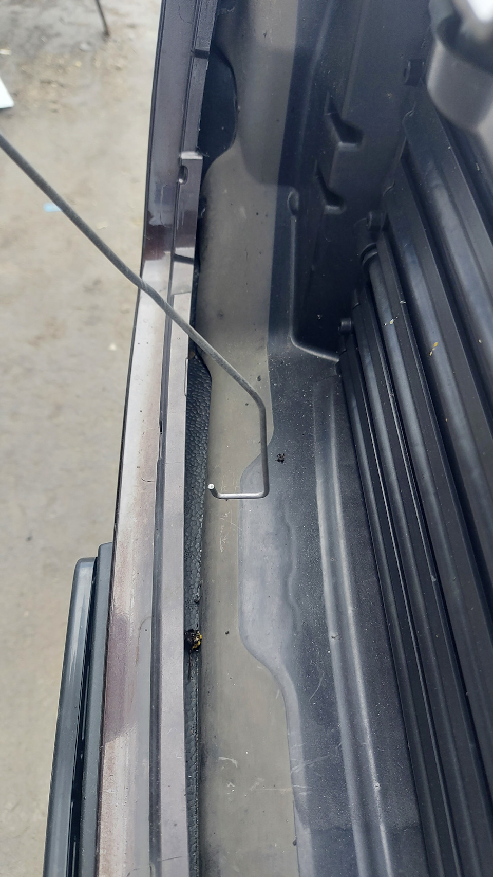 вот примерно таким образом, потянув сквозь решетку вверх, можно надавить на стопор защелки. — Volvo XC90 (2G)