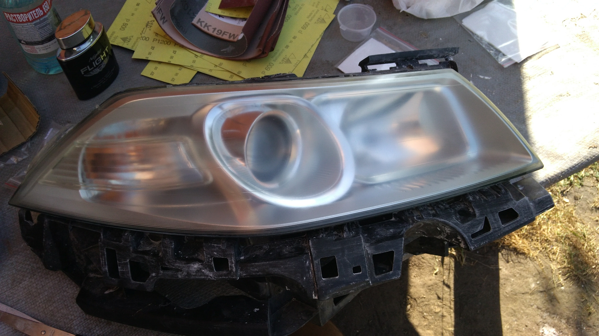 Процесс шлифовки фары наждачной бумагой