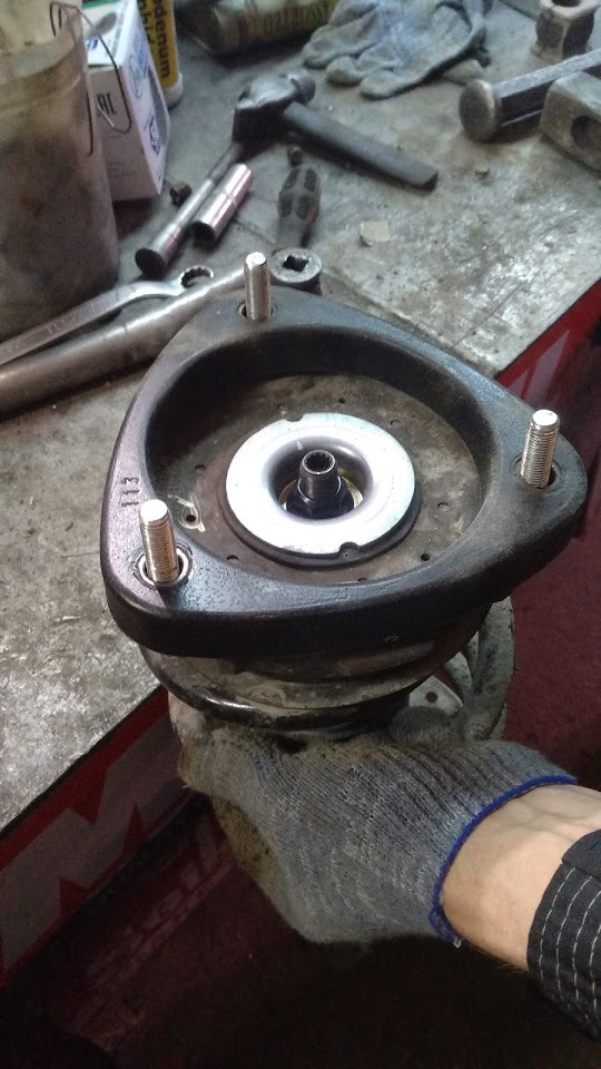 05. Przód: poluzuj obejmę/śrubę zacisku zwrotnicy trzymającą kolumnę; podeprzyj zwrotnicę. — Hyundai Santa Fe TM