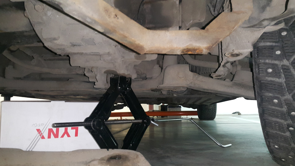 Если заранее повернуть колёса вправо, то можно подсунуть под коробку штатный домкрат и свободно крутить его ручку в образовавшемся пространстве под колесом. — Mazda 3 (1G) BK