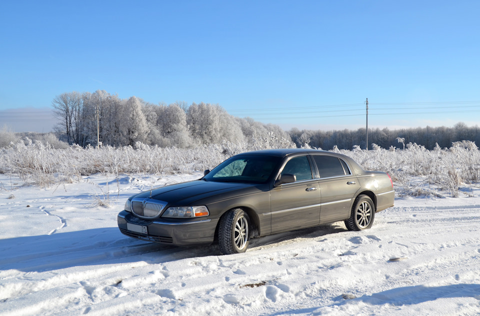 Посреди поля. На заднем плане лес и дорога. — Lincoln Town Car III