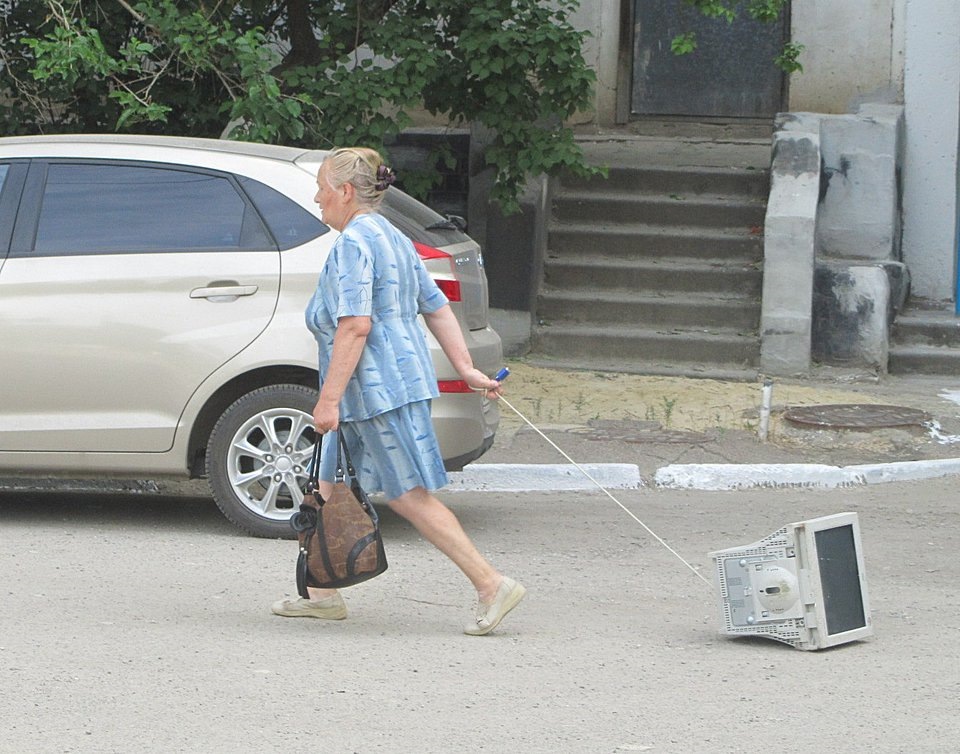 Сломался. Женщина тащит компьютер. Женщина несет телевизор. Бабушка выгуливает компьютер. Несет компьютер по улице.