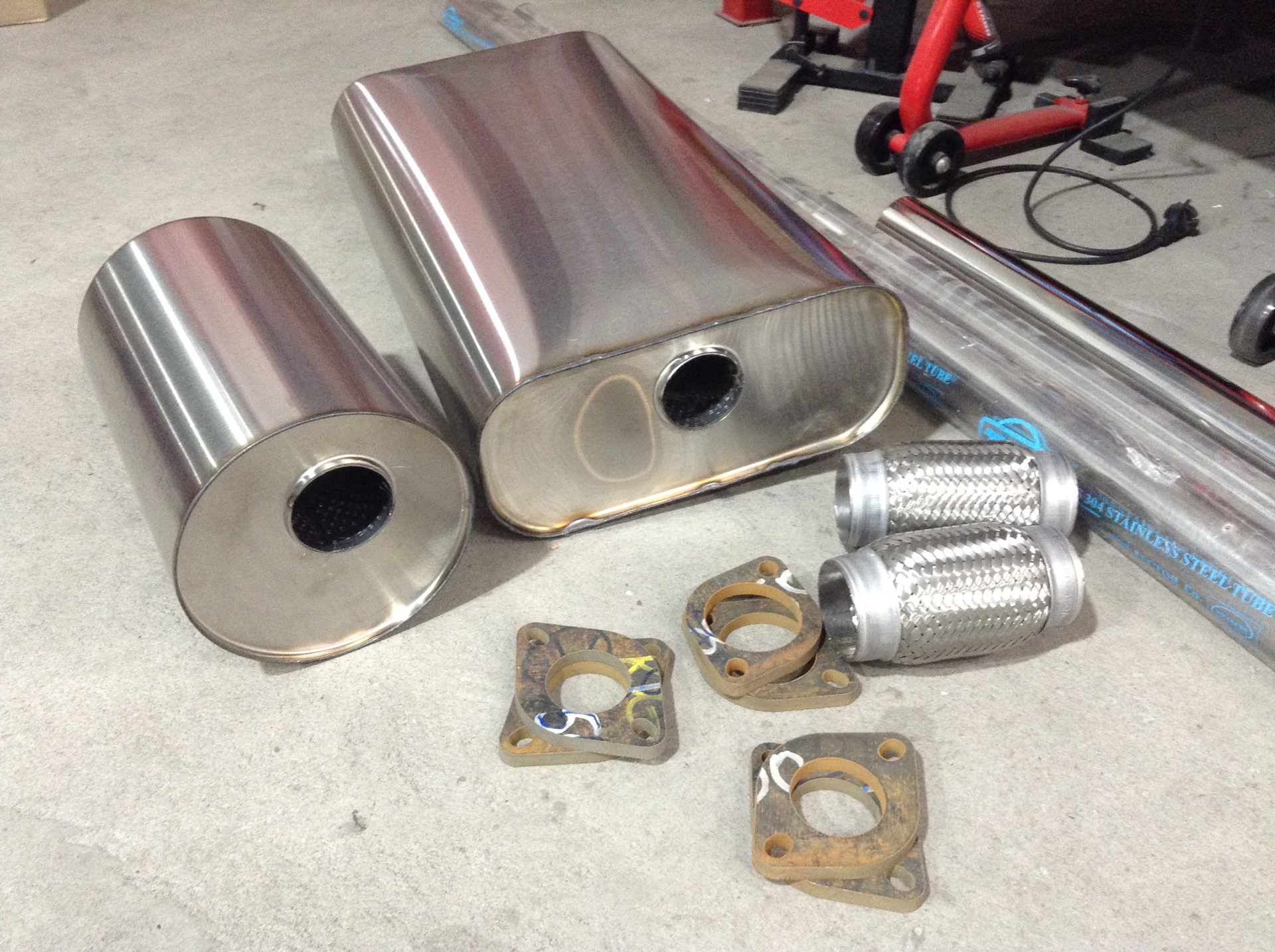 Производители глушителей. Изготовление глушителя для авто. Много выхлопных труб. Универсальные прямоточные глушители 65 мм. Хранение глушителей на складе.