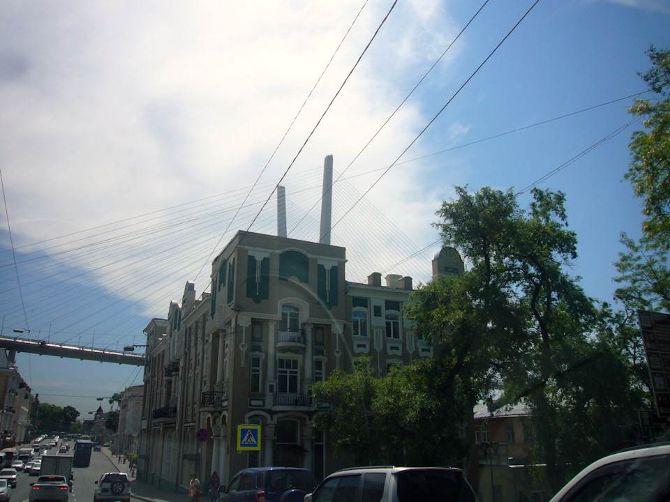 Непривычные и красивые виды открываются при передвижении по улицам Владивостока. Золотой мост возвышается над зданиями старой застройки. Современный хайтек на фоне классической архитектуры выглядит сверх футуристично. — Nissan Serena Mk IV (C26)