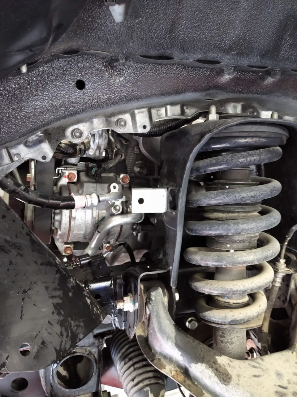 Снятый резиновый щиток. В глубине за стойкой есть небольшой болт-заглушка, вот его и нужно выкрутить. — Mitsubishi Pajero Sport (3G)