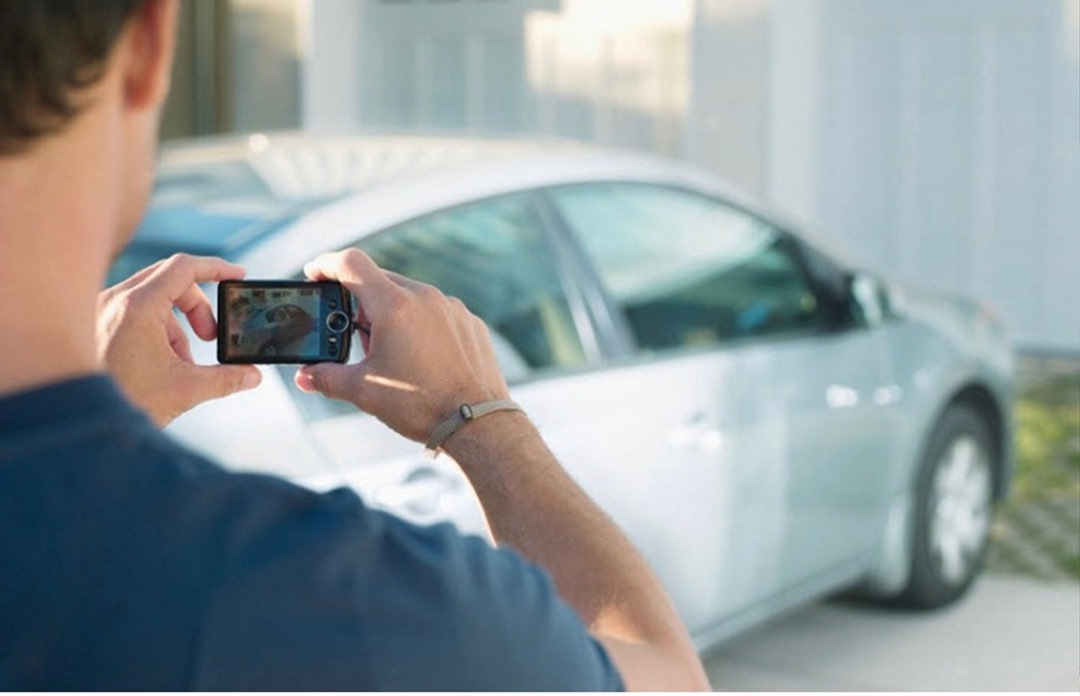 человек фотографирует автомобиль на телефон